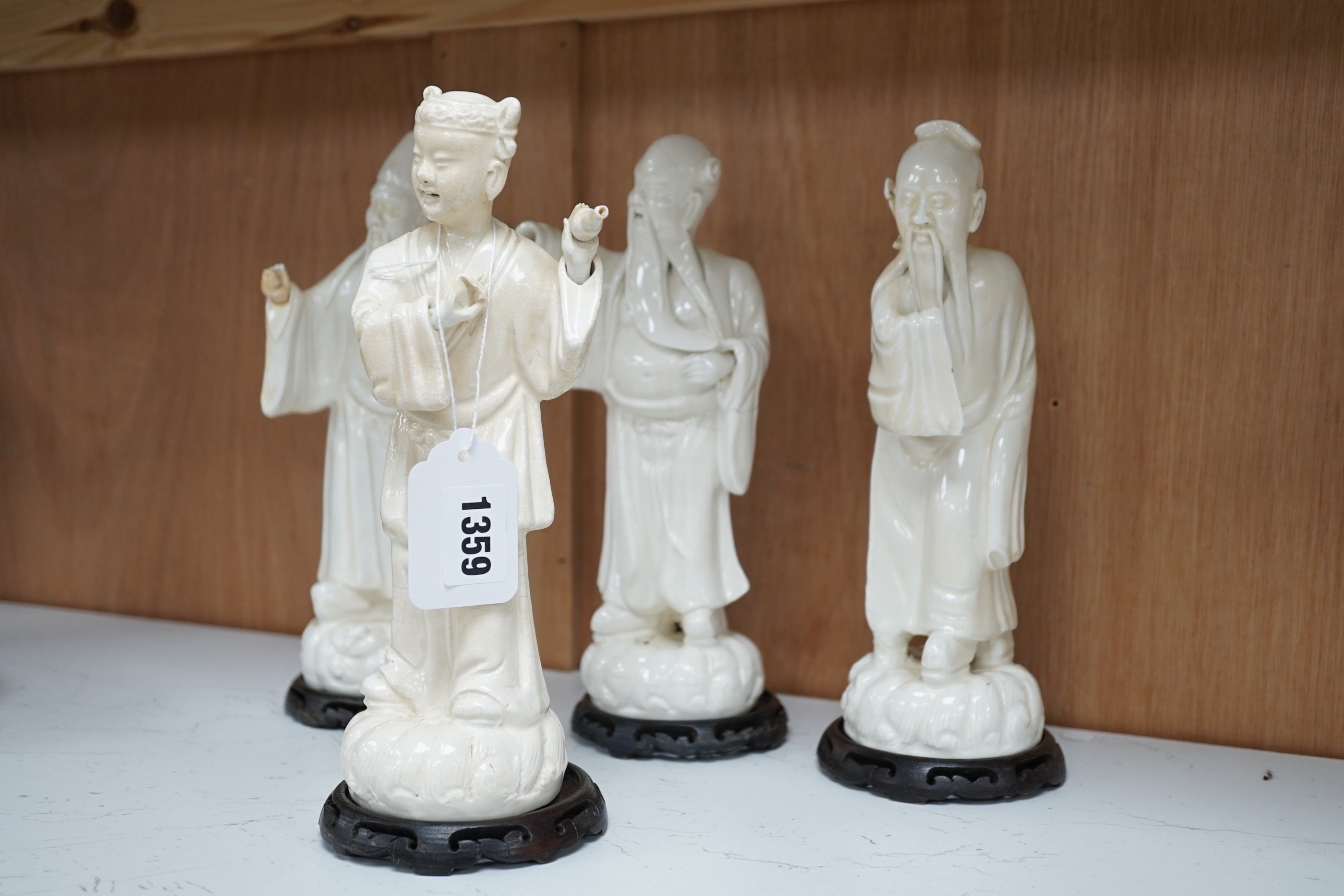 Seven Chinese blanc de Chine figures of immortals, each raised on carved hardwood bases, the largest 24cm high